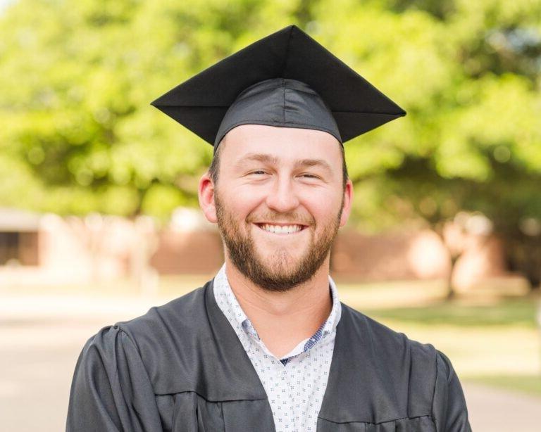 Grant Mitzelfelt smiles wearing his graduation cap and gown.